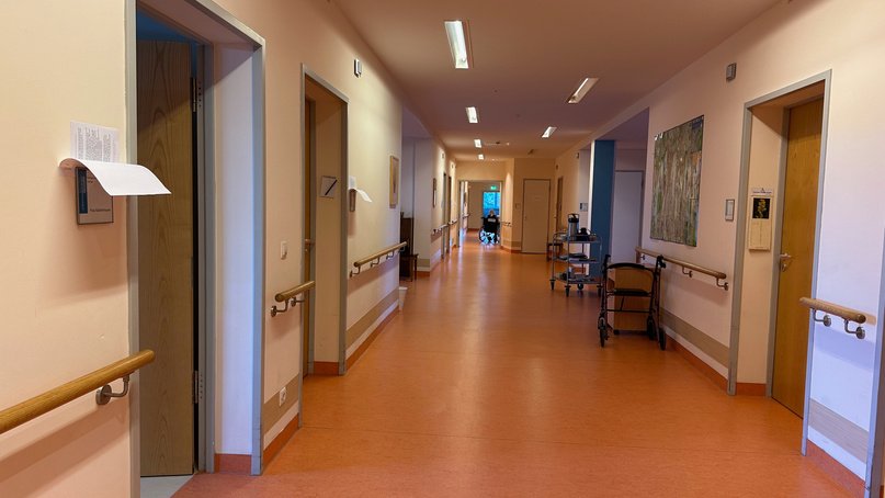 Langer Flur mit Handläufen, pastellfarben gestrichenen Wänden und orangefarbenem Boden
